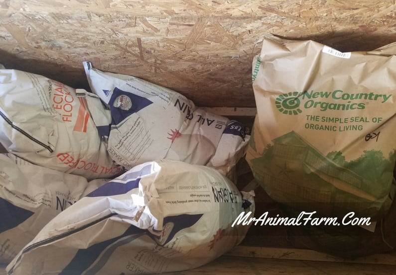 bags of chicken feed in wooden feed bin.