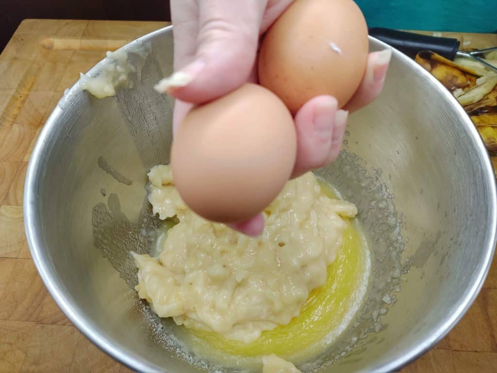 2 large eggs over bowl of banana bread batter