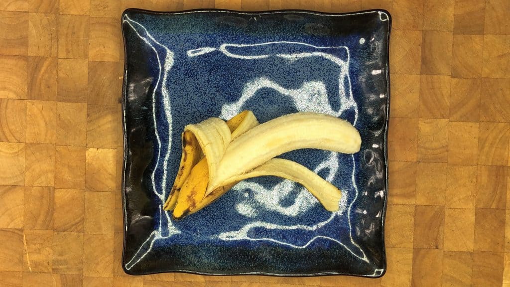 half peeled banana on blue plate