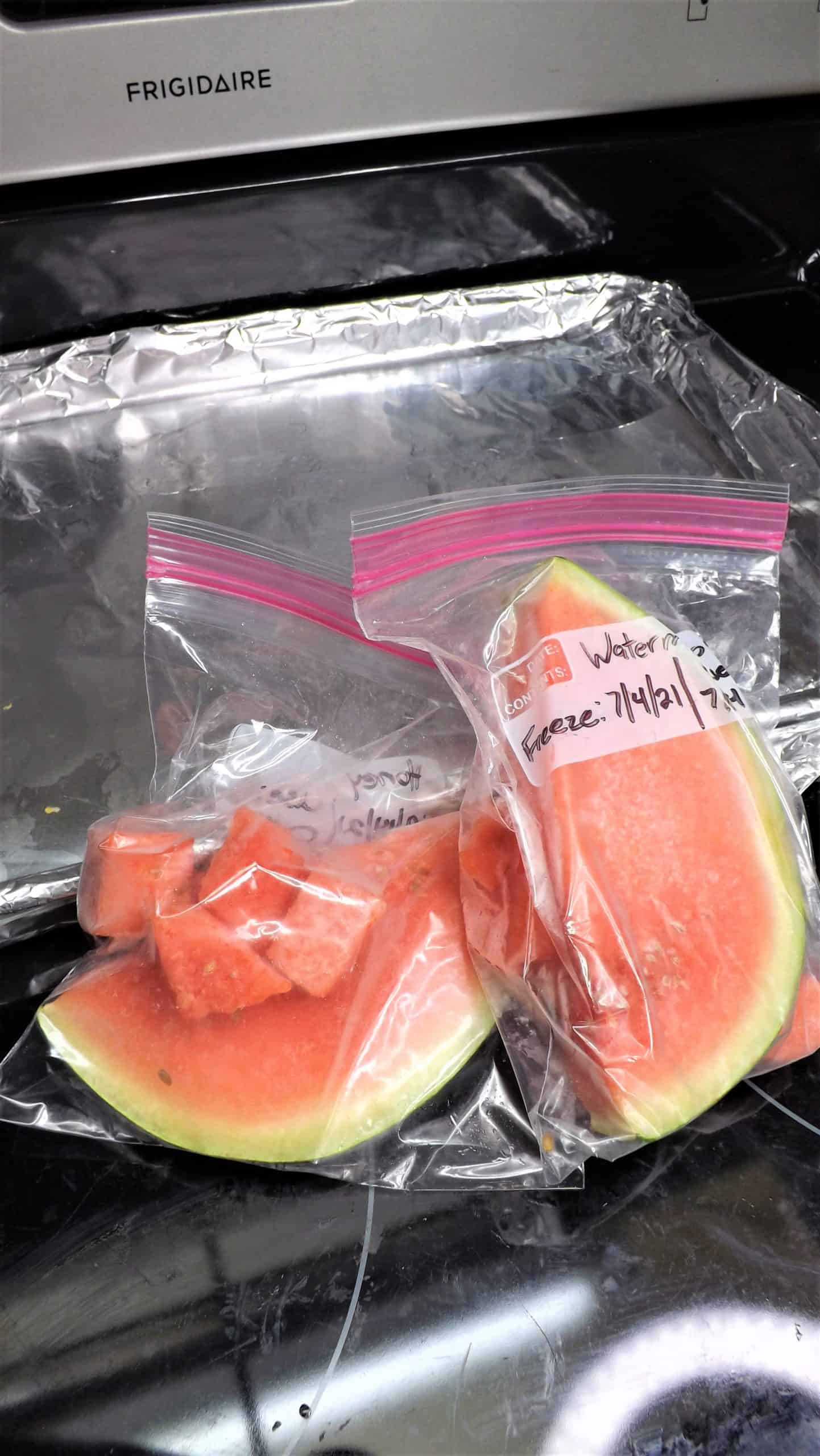 freezer bags of frozen watermelon in front of baking pan wrapped in foil
