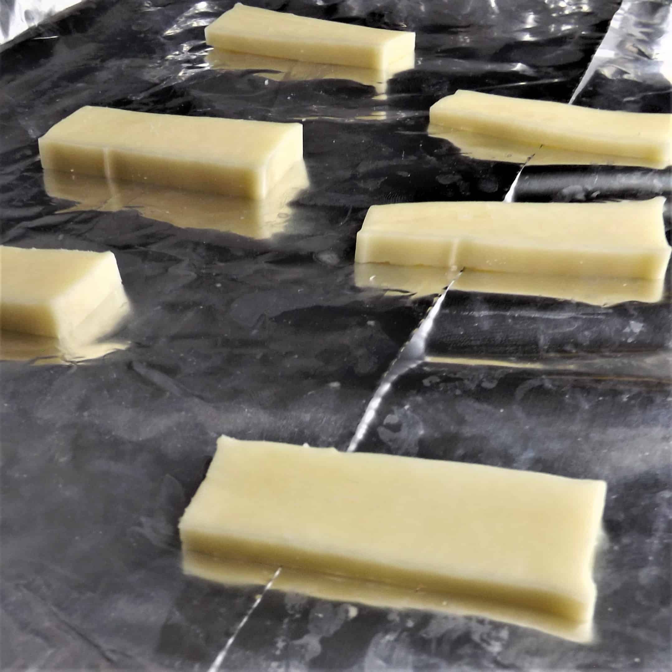 frozen mozzarella slices on baking pan wrapped in foil