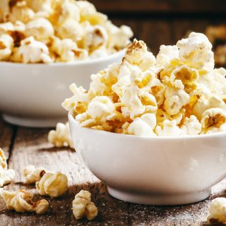 Sweet popcorn in white bowls, vintage wooden background, selective focus