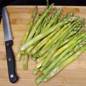 fresh asparagus on cutting board with knife