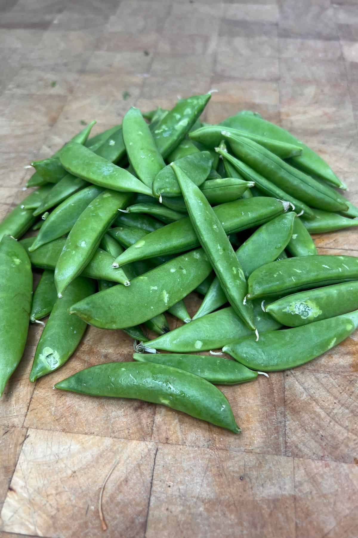 Sugar snap peas on a wooden table.